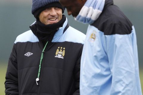 Manchester City's manager Roberto Mancini (L) talks with Yaya Toure during a training session at the club's Carrington training complex in Manchester, northern England, March 14, 2012. Manchester City are set to play Sporting Lisbon in the Europa League on Thursday. REUTERS/Phil Noble (BRITAIN - Tags: SPORT SOCCER)