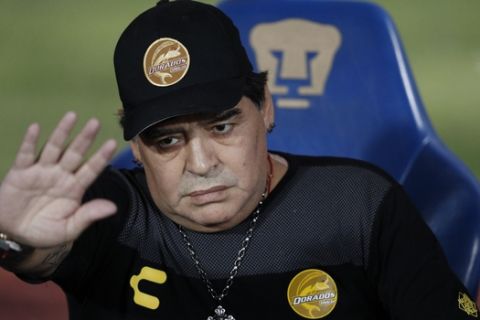 Dorados' head coach Diego Maradona waves as he takes his seat on the bench ahead of the start of Dorados' Copa MX quarterfinal match against Pumas at Olympic University Stadium in Mexico City, Tuesday, March 12, 2019. (AP Photo/Rebecca Blackwell)