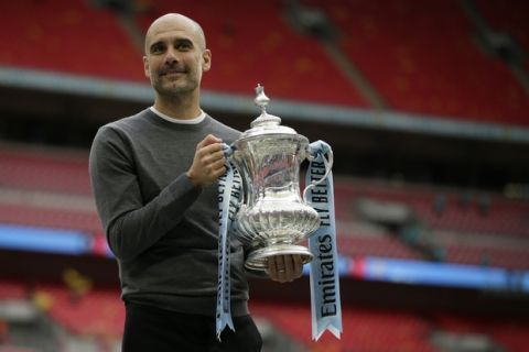 Manchester City's manager Pep Guardiola poses for a picture as lifts the trophy after winning the English FA Cup Final soccer match between Manchester City and Watford at Wembley stadium in London, Saturday, May 18, 2019. Manchester City won 6-0. (AP Photo/Tim Ireland)
