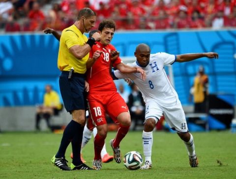 MANAUS, BRAZIL - JUNE 25:  Admir Mehmedi of Switzerland and Wilson Palacios of Honduras collide with referee Nestor Pitana during the 2014 FIFA World Cup Brazil Group E match between Honduras and Switzerland at Arena Amazonia on June 25, 2014 in Manaus, Brazil.  (Photo by Stu Forster/Getty Images)