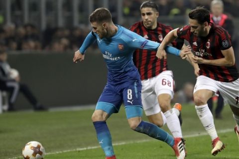 Arsenal's Aaron Ramsey, left, duels for the ball with AC Milan's Ricardo Rodriguez, center, and AC Hakan Calhanoglu during the Europa League round of 16 first-leg soccer match between AC Milan and Arsenal, at the Milan San Siro Stadium, Italy, Thursday, March 8, 2018. (AP Photo/Luca Bruno)