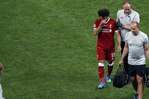 Liverpool's Mohamed Salah leaves the pitch after a collision with Real Madrid's Sergio Ramos during the Champions League Final soccer match between Real Madrid and Liverpool at the Olimpiyskiy Stadium in Kiev, Ukraine, Saturday, May 26, 2018. (AP Photo/Darko Vojinovic)