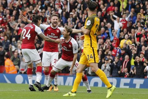Arsenal's Nacho Monreal , center, celebrates with teammates after scoring during the English Premier League soccer match between Arsenal and Brighton and Hove Albion at the Emirates Stadium in London, Sunday, Oct. 1, 2017.(AP Photo/Frank Augstein)