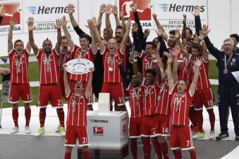 Bayern's Philipp Lahm lifts the trophy as his team celebrate winning the Bundesliga title after the German first division Bundesliga soccer match between FC Bayern Munich and SC Freiburg at the Allianz Arena stadium in Munich, Germany, Saturday, May 20, 2017. (AP Photo/Matthias Schrader)