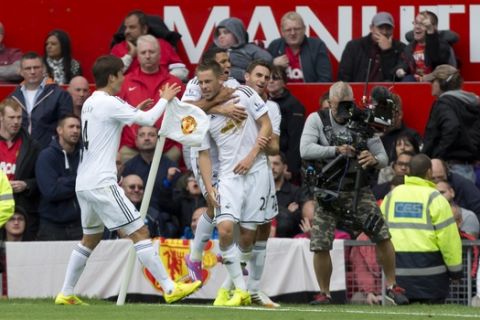 Swansea City's Gylvi Sigurdsson, lower center, celebrates with teammates after scoring against Manchester United during their English Premier League soccer match at Old Trafford Stadium, Manchester, England, Saturday Aug. 16, 2014. (AP Photo/Jon Super)  
