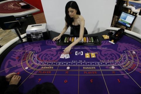 In this photo taken on Thursday, May 23, 2013, an attendant demonstrates the game of baccarat on a baccarat gaming table during the Global Gaming Expo Asia in Macau. Almost all of Macaus $38 billion in gambling revenue last year - six times more than the Las Vegas Strip - came from card game, much of it from Chinese high-rollers betting borrowed money and dwarfing the takings from slots, blackjack or roulette. Wherever you go in the former Portuguese colony, youll see chain-smoking Chinese gamblers crowded around baccarat tables as players peel back their cards, hoping their luck will give them a good hand. (AP Photo/Kin Cheung)