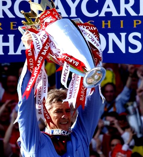 FILE - In this Saturday, May 15, 2004 file photo. Arsenal's manager, Arsene Wenger holds up the English Premiership Trophy for Arsenal winning the 2003/2004 season at Highbury, London. Wenger will stay on as Arsenal manager, earning a new two-year contract on Wednesday, May 31, 2017 despite missing out on Champions League qualification. (AP Photo/Max Nash, File)