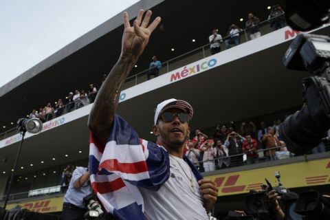 Mercedes driver Lewis Hamilton, of Britain, flashes number four as he celebrates with his teammates at the pit lane after the Formula One Mexico Grand Prix auto race at the Hermanos Rodriguez racetrack in Mexico City, Sunday, Oct. 29, 2017. Hamilton won his fourth career Formula One season championship on Sunday with a ninth-place finish at the Mexican Grand Prix in a race won by Red Bull's Max Verstappen. (AP Photo/Rebecca Blackwell)