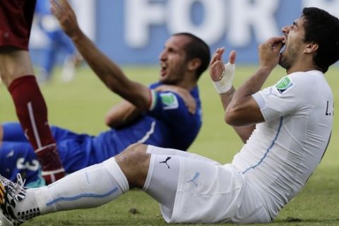 FILE - In this June 24, 2014 file photo, Uruguay's Luis Suarez holds his teeth after biting Italy's Giorgio Chiellini's shoulder during the group D World Cup soccer match between Italy and Uruguay at the Arena das Dunas in Natal, Brazil. On Thursday, June 26, 2014, FIFA banned Suarez for 9 games and 4 months for biting his opponent at the World Cup. (AP Photo/Ricardo Mazalan, File)