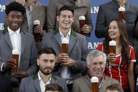 Bayern's James Rodriguez, center, and team mate David Alaba, left, pose in traditional Bavarian clothes during a photo-shooting of a brewing company in Munich, Germany, Wednesday, Sept. 13, 2017. Mueller celebrates his 28th birthday today. (AP Photo/Matthias Schrader)