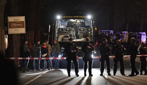FILE - In this April 11, 2017 file photo police officers stand in front of Dortmund's damaged team bus after explosions which injured two people before the Champions League quarterfinal soccer match between Borussia Dortmund and AS Monaco in Dortmund, western Germany. On Thursday, Dec. 21, 2017 a man will go on trial. He is charged with the attempted murder of Borussia's soccer team by detonating homemade bombs when traveling to the match.  (AP Photo/Martin Meissner, file)