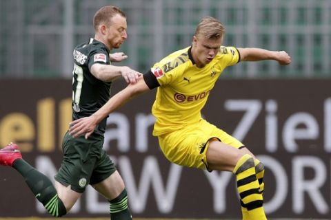 Dortmund's Erling Haaland controls the ball next to Wolfsburg's Maximilian Arnold, left, during the German Bundesliga soccer match between VfL Wolfsburg and Borussia Dortmund in Wolfsburg, Germany, Saturday, May 23, 2020. The German Bundesliga is the world's first major soccer league to resume after a two-month suspension because of the coronavirus pandemic. (AP Photo/Michael Sohn, Pool)