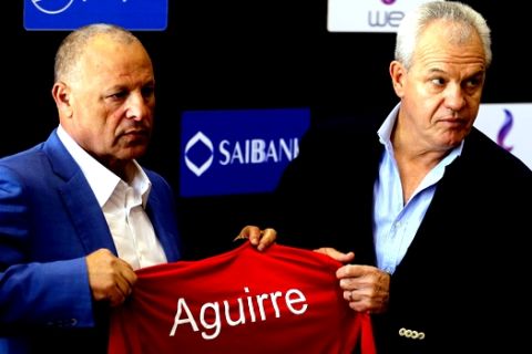 Egypt's new national football team coach Javier Aguirre, right, receives a team T-shirt from Hany Abo Rida, the Football Association chairman, during a press conference in Cairo, Egypt, Thursday, Aug. 2, 2018. Aguirre, a Mexican, will be paid $1.4 million a year and will receive a $500,000 bonus if Egypt qualifies for the World Cup in 2022 in Qatar, Abo Rida said. (AP Photo/Amr Nabil)