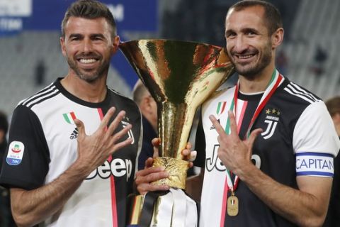 Juventus' Andrea Barzagli, left, and Juventus' Giorgio Chiellini pose with the Serie A soccer title trophy, at the Allianz Stadium, in Turin, Italy, Wednesday, April 3, 2019. (AP Photo/Antonio Calanni)