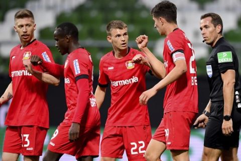 Leverkusen's Kai Havertz , center, cheers with his teammates Mitchel Weiser , from left to right, Moussa Diaby and Kai Havertz next to referee Tobias Stieler after his goal during the German Bundesliga soccer match between Werder Bremen and Bayer Leverkusen 04 in Bremen, Germany, Monday, May 18, 2020. The German Bundesliga becomes the world's first major soccer league to resume after a two-month suspension because of the coronavirus pandemic. (AP Photo/Stuart Franklin, Pool)
