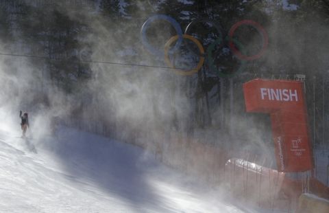 The finish line and Olympic rings shrouded in snow as they carry ski gates after the women's giant slalom was postponed due to high winds at the 2018 Winter Olympics at the Yongpyong Alpine Center, Pyeongchang, South Korea, Monday, Feb. 12, 2018. (AP Photo/Michael Probst)