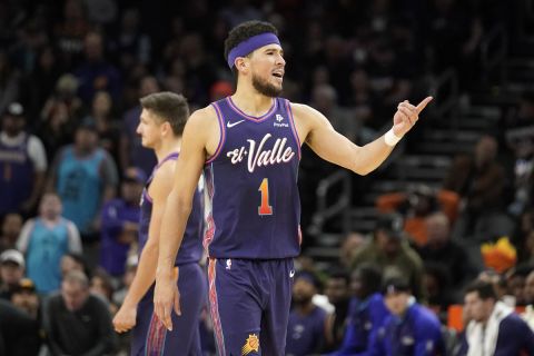Phoenix Suns' Devin Booker (1) gestures toward the Washington Wizards' bench during the second half of an NBA basketball game in Phoenix, Sunday, Dec. 17, 2023. (AP Photo/Darryl Webb)