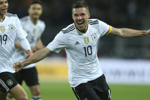 Germany's Lukas Podolski, right, celebrates after scoring the opening goal during the friendly soccer match between Germany and England in Dortmund, Germany, Wednesday, March 22, 2017. (Ina Fassbender/dpa via AP)