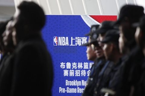 Security personnel line up near a promotion board for an NBA preseason game to be held at the Mercedes Benz Arena in Shanghai, China, Thursday, Oct. 10, 2019. All media events such as news conferences have been canceled inside the arena hosting Thursday's NBA preseason game in China between the Los Angeles Lakers and Brooklyn Nets, though the matchup itself remains on as scheduled. (AP Photo)