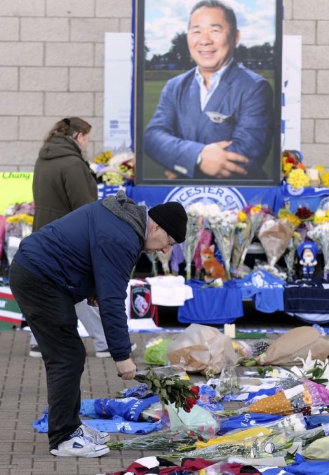 A man lays flowers outside Leicester City Football Club, Leicester, England, Monday Oct. 29, 2018, after a helicopter crashed in flames Saturday. Vichai Srivaddhanaprabha, the Thai billionaire owner of Premier League team Leicester City was among five people who died after his helicopter crashed and burst into flames shortly after taking off from the soccer field, the club said Sunday. (AP Photo/Rui Vieira)