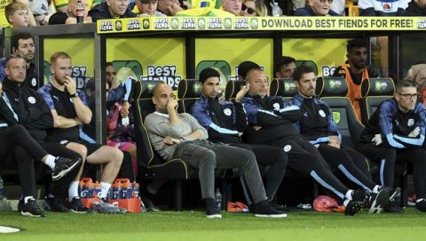 Manchester City manager Pep Guardiola, center left, looks dejected on the bench with his backroom staff during the English Premier League soccer match between Norwich City and Manchester City at Carrow Road, Norwich, England, Saturday, Sept. 14, 2019. (Joe Giddens/PA via AP)