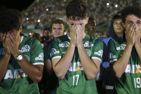 Chapecoense soccer players who did not travel with their team on a flight to Colombia that crashed, mourn during a tribute to the crash victims at Arena Condado stadium in Chapeco, Brazil, Wednesday, Nov. 30, 2016. Authorities were working to finish identifying the bodies before repatriating them to Brazil. (AP Photo/Andre Penner)