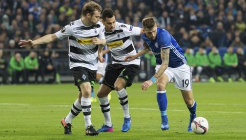 Schalke's Guido Burgstaller, right, and Gladbach's Timothee Kolodziejczak, center, and Tony Jantschke in action during the Europa League round of 16 first leg soccer match between FC'Schalke 04 and Borussia Moenchengladbach at the Veltins Arena in Gelsenkirchen, Germany, Thursday, March 9, 2017. (Guido Kirchner/DPA via AP)