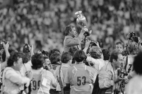 French soccer team coach Michel Hidalgo raises the 1984 European Championship cup as he is carried across the Parc des Princes Stadium in Paris by his players after France won the finals against Spain on a 2-0 score, June 27, 1984.  (AP Photo)