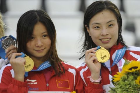 China's He Zi (L) and Wu Minxia (R) pose on the podium with their gold medals after winning the women's 3-metre synchronised springboard final diving event at the FINA World Championships at the outdoor diving pool of the Oriental Sports Centre in Shanghai on July 16, 2011. AFP PHOTO / PHILIPPE LOPEZ (Photo credit should read PHILIPPE LOPEZ/AFP/Getty Images)