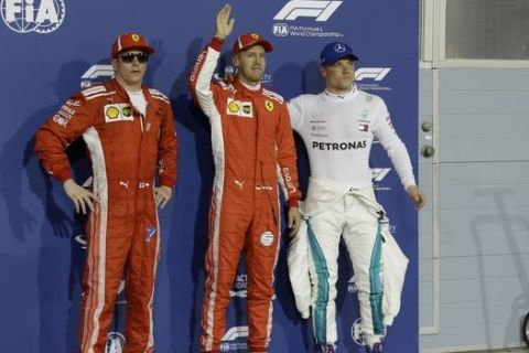 Ferrari driver Sebastian Vettel of Germany, center, who earned pole position, Mercedes driver Valtteri Bottas of Finland, right, who came in third and Ferrari driver Kimi Raikkonen of Finland, who earned the second best time, posing for photos after the qualifying for the Bahrain Formula One Grand Prix, at the Formula One Bahrain International Circuit in Sakhir, Bahrain, Saturday, April 7, 2018. The Bahrain Formula One Grand Prix will take place here on Sunday. (AP Photo/Luca Bruno)