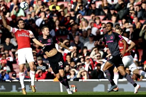 Arsenal's Sokratis Papastathopoulos, left, jumps for the ball with Everton's Gylfi Sigurdsson during an English Premier League soccer match between Arsenal and Everton at the Emirates Stadium in London, Sunday Sept. 23, 2018. (AP Photo/Tim Ireland)