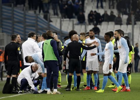 The referee speaks to players as the match is suspended during a French League One soccer match between Olympique Marseille and Lille at the Stade Velodrome in Marseille, France, Friday, Jan. 25, 2019. (AP Photo/Claude Paris)