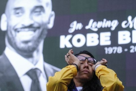 Nicole Mascarenhas, wipes her eyes in front of a screen with the late Kobe Bryant at a memorial for Kobe Bryant near Staples Center Monday, Jan. 27, 2020, in Los Angeles. Bryant, the 18-time NBA All-Star who won five championships and became one of the greatest basketball players of his generation during a 20-year career with the Los Angeles Lakers, died in a helicopter crash Sunday. (AP Photo/Ringo H.W. Chiu)
