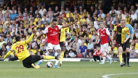 Arsenal's Pierre-Emerick Aubameyang shoots at goal as Watford's Etienne Capoue attempts to block his shot during their English Premier League soccer match between Watford and Arsenal at the Vicarage Road stadium in Watford near London, Sunday, Sept., 15, 2019. (AP Photo/Alastair Grant)