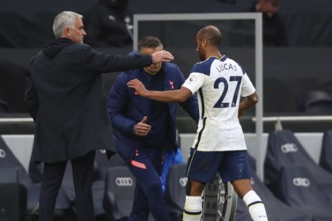 Tottenham's Lucas Moura, right, is greeted by coach Jose Mourinho as he leaves the pitch during the English Premier League soccer match between Tottenham and Newcastle at the Tottenham Hotspur Stadium in London, Sunday, Sept. 27, 2020. (Clive Rose/Pool via AP)