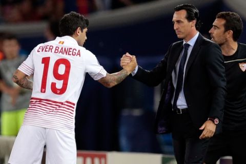 Sevillas Ever Banega, center, shakes hands with Sevillas head coach Unai Emery after scoring the opening goal during the UEFA Super Cup soccer match between FC Barcelona and Sevilla FC at the Boris Paichadze Dinamo Arena stadium, in Tbilisi, Georgia, on Tuesday, Aug. 11, 2015. (AP Photo/Ivan Sekretarev)