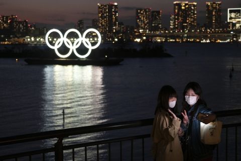 Two women take a selfie with the Olympic rings in the background in the Odaiba section of Tokyo, Thursday, March 12, 2020. Tokyo Governor Yuriko Koike spoke Thursday after the World Health Organization labeled the spreading virus a "pandemic," a decision almost certain to affect the Tokyo Olympics. (AP Photo/Jae C. Hong)