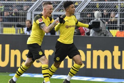 CORRECTS NAME OF THE PLAYER AT LEFT - Dortmund's Jadon Sancho, right, celebrates with teammate Dortmund's Marius Wolf after scoring during the German Bundesliga soccer match between Borussia Dortmund and FSV Mainz 05 in Dortmund, Germany, Saturday, April 13, 2019. (AP Photo/Martin Meissner)