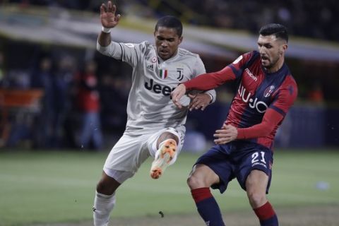 Juventus' Douglas Costa, left, challenges for the ball with Bologna's Roberto Soriano during a round of 16, Italian Cup soccer match between Bologna and Juventus at the Renato Dall'Ara stadium in Bologna, Italy, Saturday, Jan. 12, 2019. (AP Photo/Luca Bruno)