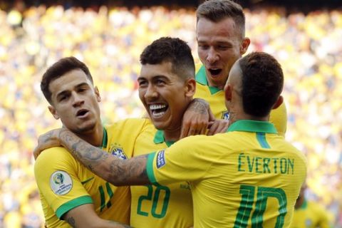 Brazil's Roberto Firmino, center, celebrates scoring his side's second goal against Peru with teammates Phlippe Coutinho, left, and Everton, right, during a Copa America Group A soccer match at the Arena Corinthians in Sao Paulo, Brazil, Saturday, June 22, 2019. (AP Photo/Victor R. Caivano)
