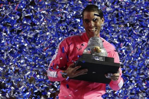 Spain's Rafael Nadal bites his trophy as confetti falls, after Nadal defeated Taylor Fritz, of the United States, 6-3, 6-2 in the men's final of the Mexican Open tennis tournament in Acapulco, Mexico, Saturday, Feb. 29, 2020. (AP Photo/Rebecca Blackwell)
