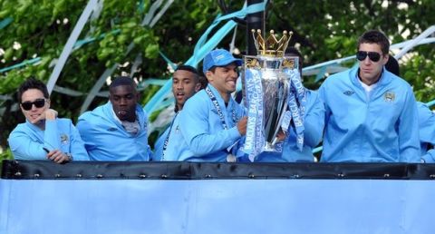 Manchester City's Argentinian forward Sergio Aguero (2R) and Manchester City's Romanian goalkeeper Costel Pantilimon hold the trophy on an open topped bus as they celebrate becoming English Premier League champions in a parade leaving from Mancheter Town Hall in Manchester, northwest England, on May 14, 2012. Manchester City beat their rivals Manchester United on goal difference to be crowned champions on the final day of the season with a 3-2 victory over Queens Park Rangers. AFP PHOTO/PAUL ELLIS        (Photo credit should read PAUL ELLIS/AFP/GettyImages)