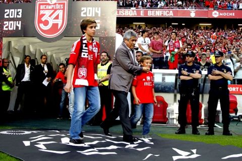 Young Benfica supporters brothers Goncalo and Tomas Magalhaes, centre left and right, enter the pitch with Benfica's president Luis Felipe Vieira, centre, at the end of the Portuguese league soccer match between Benfica and Maritimo at the Benfica's Luz stadium, in Lisbon, Portugal, Saturday, May 23, 2015. Tomas and Goncalo are the children of Jose Magalhaes who was beating and arrested by a policeman in front of them last Sunday outside a stadium after a Benfica match in Guimaraes, north Portugal, sparking a national scandal. Benfica won its 34th Portuguese league soccer title, second in a row, ahead of runners-up Porto. (AP Photo/Francisco Seco)