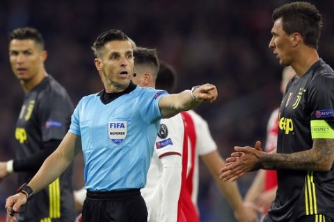 Referee Carlos del Cerro Grande, center, discusses with Juventus forward Mario Mandzukic, right, during the Champions League quarterfinal, first leg, soccer match between Ajax and Juventus at the Johan Cruyff ArenA in Amsterdam, Netherlands, Wednesday, April 10, 2019. (AP Photo/Peter Dejong)