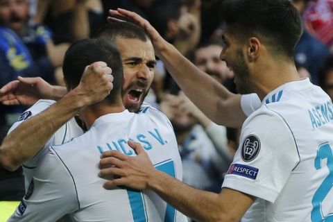 Real Madrid's Karim Benzema is congratulated by his teammates Lucas Vazquez, left, and Marco Asensio, right, after scoring their side's first goal during the Champions League semifinal second leg soccer match between Real Madrid and FC Bayern Munich at the Santiago Bernabeu stadium in Madrid, Spain, Tuesday, May 1, 2018. (AP Photo/Paul White)