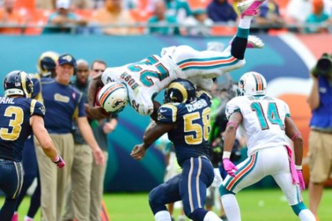 Oct.14, 2012;  Miami, FL, USA; Miami Dolphins running back Reggie Bush (22) leaps over St. Louis Rams outside linebacker Jo-Lonn Dunbar (58) during the fourth quarter at Sun Life Stadium. Dolphins won 17-14. Mandatory Credit: Steve Mitchell-US PRESSWIRE  