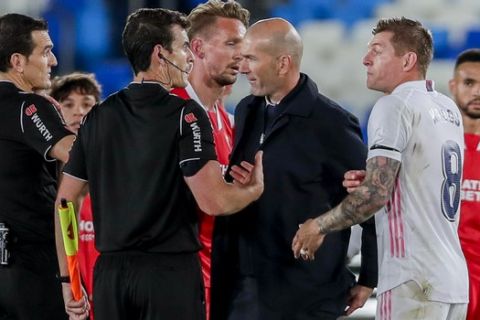 Real Madrid's head coach Zinedine Zidane talks with the referre at the end of the Spanish La Liga soccer match between Real Madrid and Sevilla at the Alfredo di Stefano stadium in Madrid, Spain, Sunday, May 9, 2021. (AP Photo/Manu Fernandez)