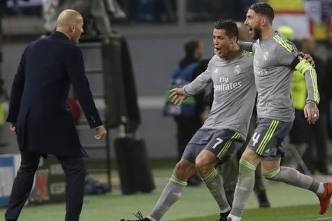 Real Madrid's Cristiano Ronaldo, center, celebrates with coach Zinedine Zidane, left, and Sergio Ramos after scoring the opening goal   during a Champions League, round of 16, first-leg soccer match between Roma and Real Madrid, at the Rome Olympic stadium, Wednesday, Feb. 17, 2016. (AP Photo/Alessandra Tarantino)