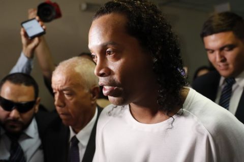 Former soccer star Ronaldinho is escorted by police to go before Judge Mirko Valinotti at the Justice Palace court in Asuncion, Paraguay, Friday, March 6, 2020.  Ronaldinho has been detained by Paraguayan police for allegedly entering the country with a falsified passport. (AP Photo/Jorge Saenz)