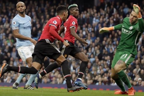 Manchester United's Chris Smalling celebrates with Manchester United's Paul Pogba, center right, after scoring his side's third goal past Manchester City goalkeeper Ederson, right, during the English Premier League soccer match between Manchester City and Manchester United at the Etihad Stadium in Manchester, England, Saturday April 7, 2018. (AP Photo/Matt Dunham)